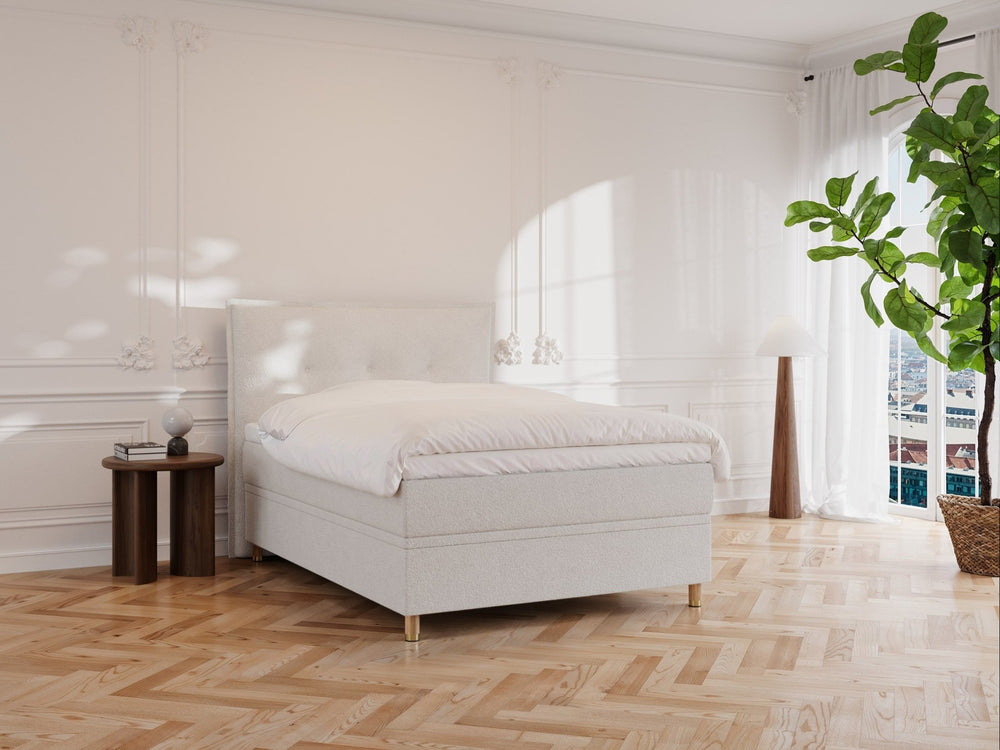 Kontinentalseng Alva 140x200 i cream bouclé, mykt polstret hodegavl, lys dyne, rom med parkett og grønn plante