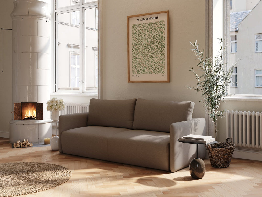 Brun sovesofa 140x200 i stoff, enkel modern form i lyst stueinteriør med peis, plante og trebord.