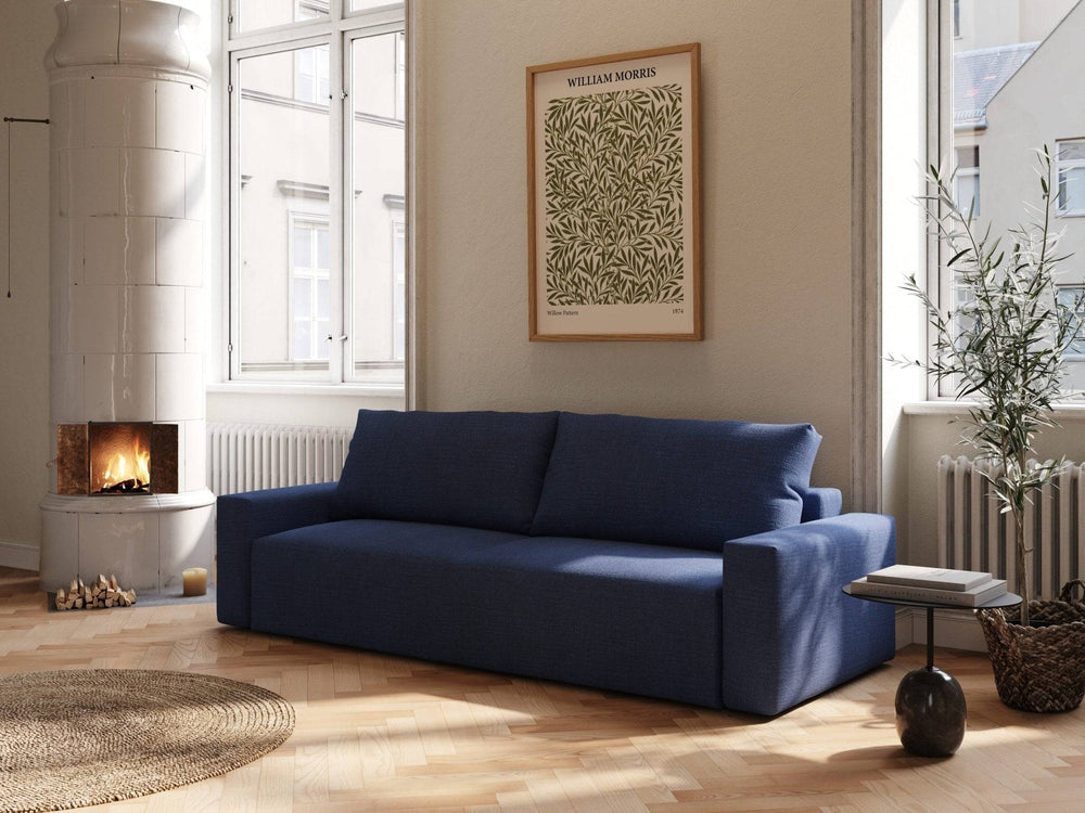 Mørkeblå sovesofa Mara 145x200 cm i vevd stoff, lav rygg og brede armlener i lyst, solfylt stuerom ved peis.