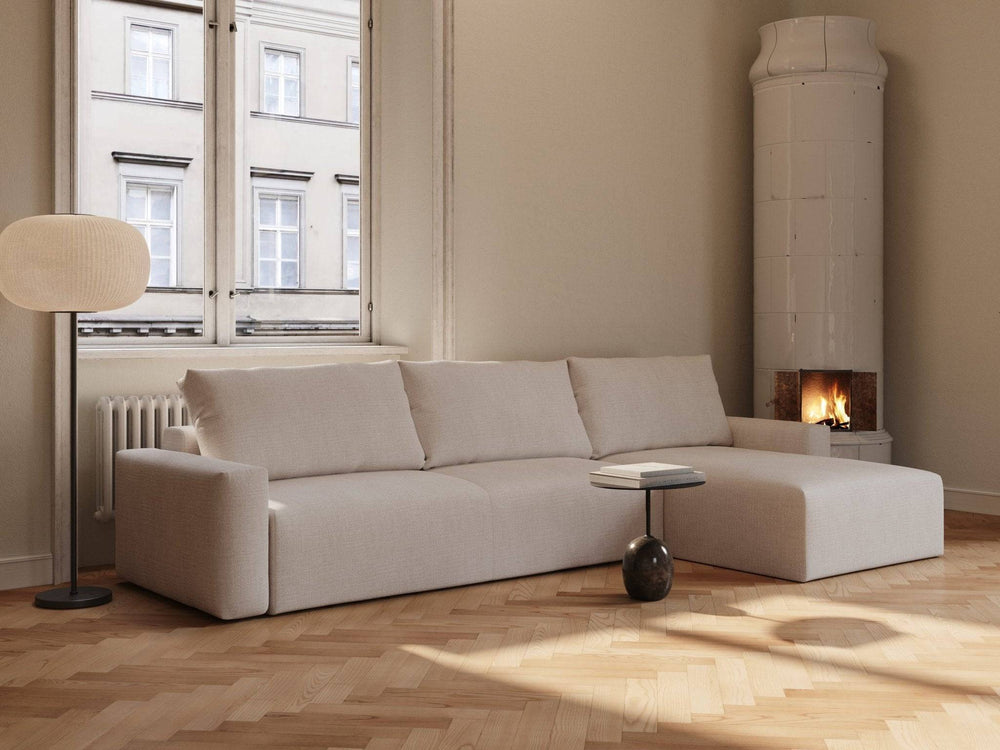 Beige Maru sovesofa 145x342 cm i linaktig stoff, hjørnemodell med løse ryggputetrekk, plassert i lyst rom ved vindu og peis.