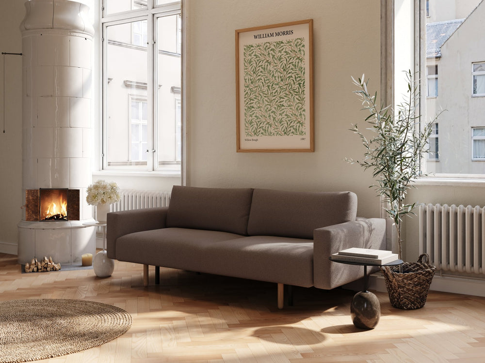 Maya sovesofa 140x200 i mørkebrun bouclé, rett form med armlene, treben i lys stue ved peis og vindu.