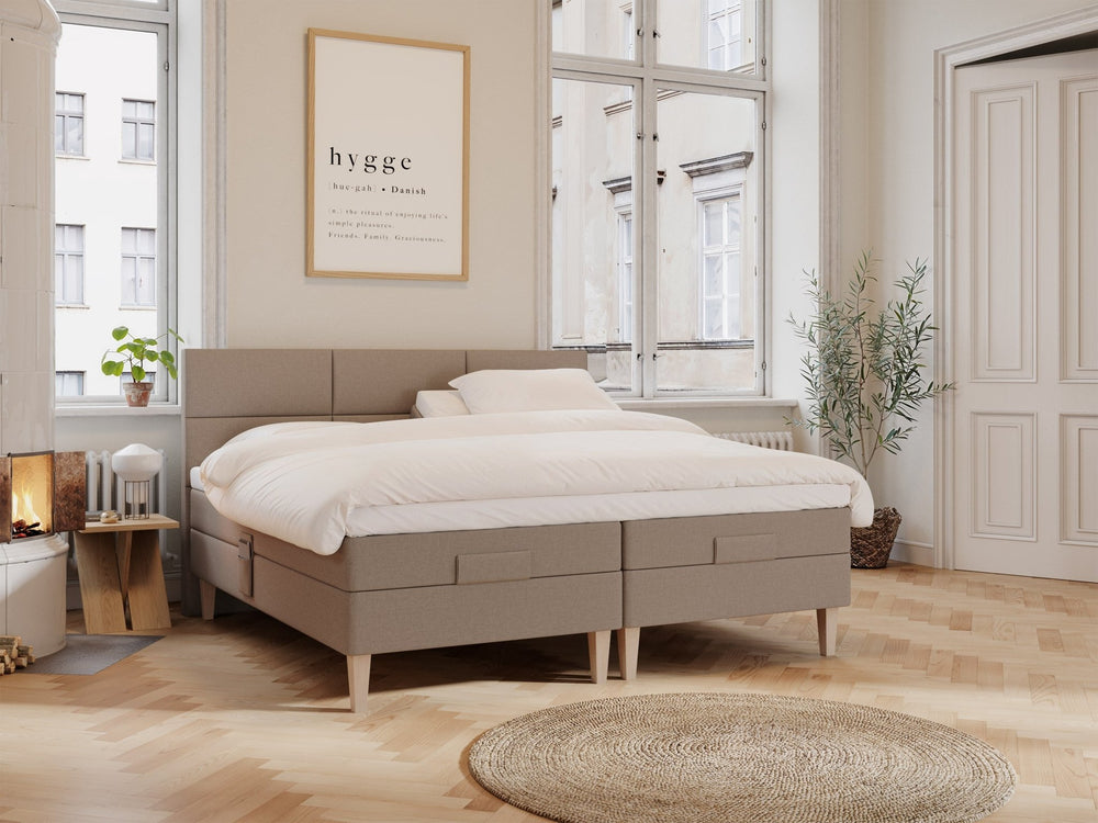 Brun regulerbar dobbeltseng 210x210 med polstret hodegjerde, lys dyne og treben i lyst, lyst rom