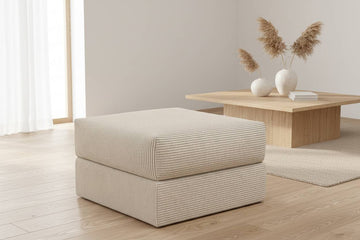 Beige rektangulær puf 75x75 med ribbet stoff, to-lags form plassert på lyst tregulv ved lavt trebord og dekor.